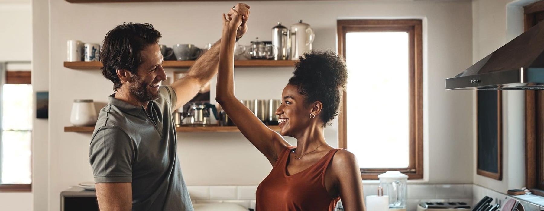 a man and a woman dance in well lit kitchen